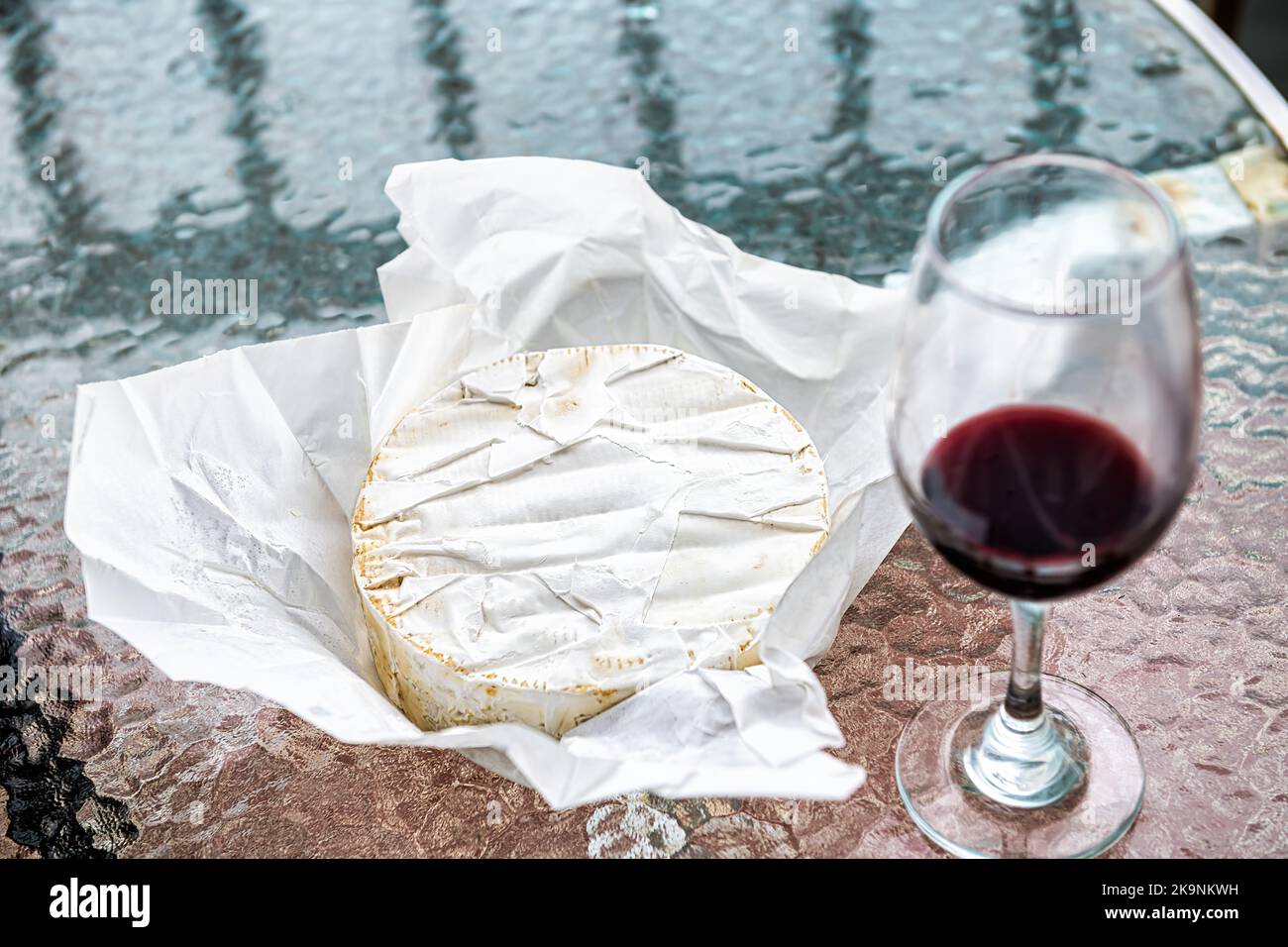 Formaggio brie francese intero carrello a ruota rotonda in confezione di carta, latte prodotto doppia crema con vino rosso in vetro su tavolo da cucina macro closeup Foto Stock