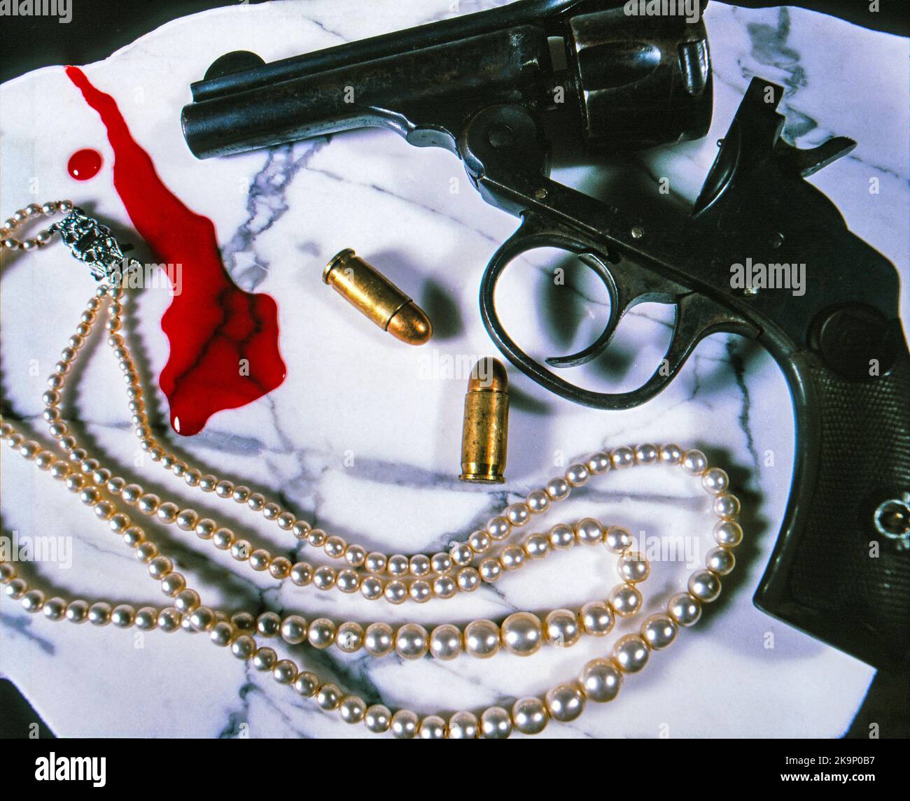 Still Life of a revolver gun, proiettili, collana di perle e sangue sparsi su sfondo di marmo bianco. Foto Stock