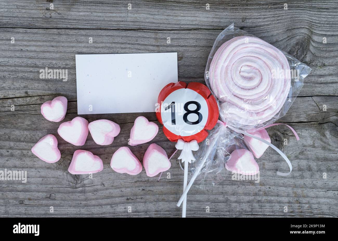 Buon 18th biglietto di auguri di compleanno e marshmallows rosa giacciono su un asse di legno Foto Stock
