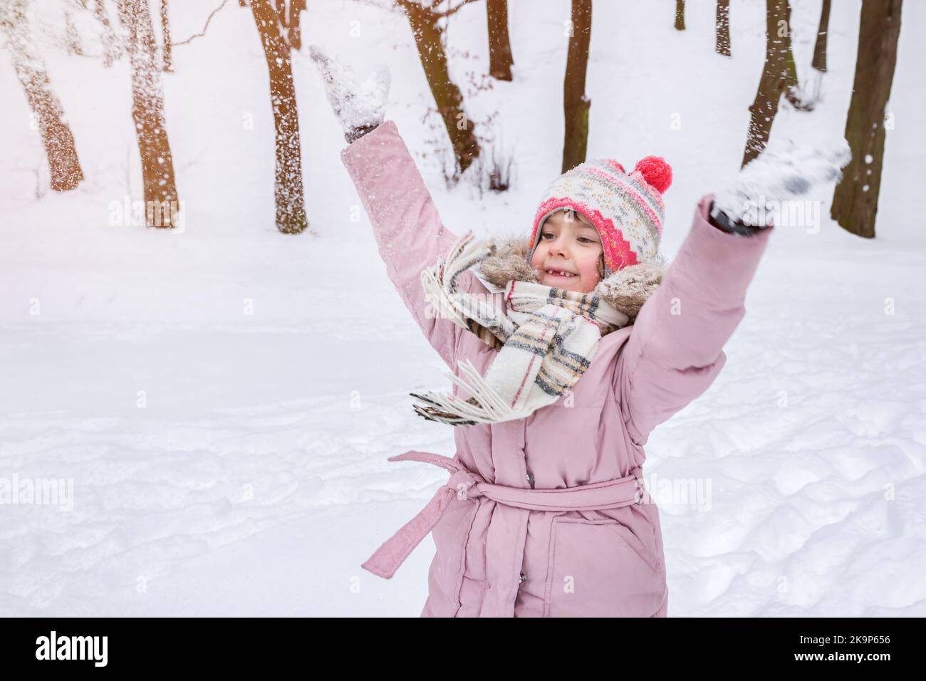 Bambina in abiti caldi gioca nel parco invernale. La vacanza invernale Foto Stock