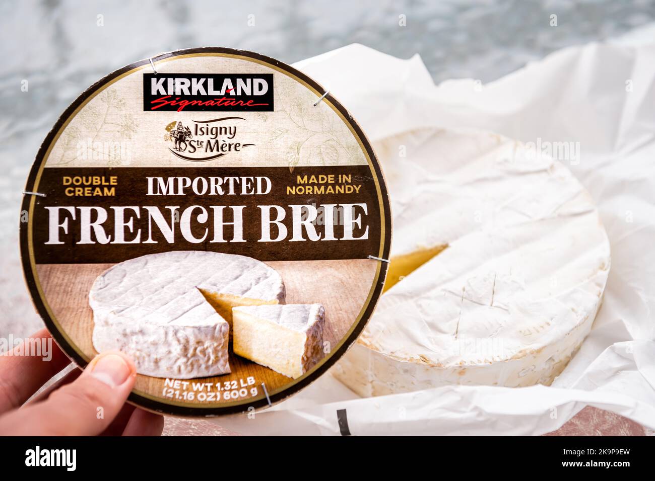 Hollywood, USA - 12 luglio 2021: Tenuta a mano Costco Kirkland marchio marchio privato marchio doppia crema francese brie formaggio da Normandia macro closeup Foto Stock