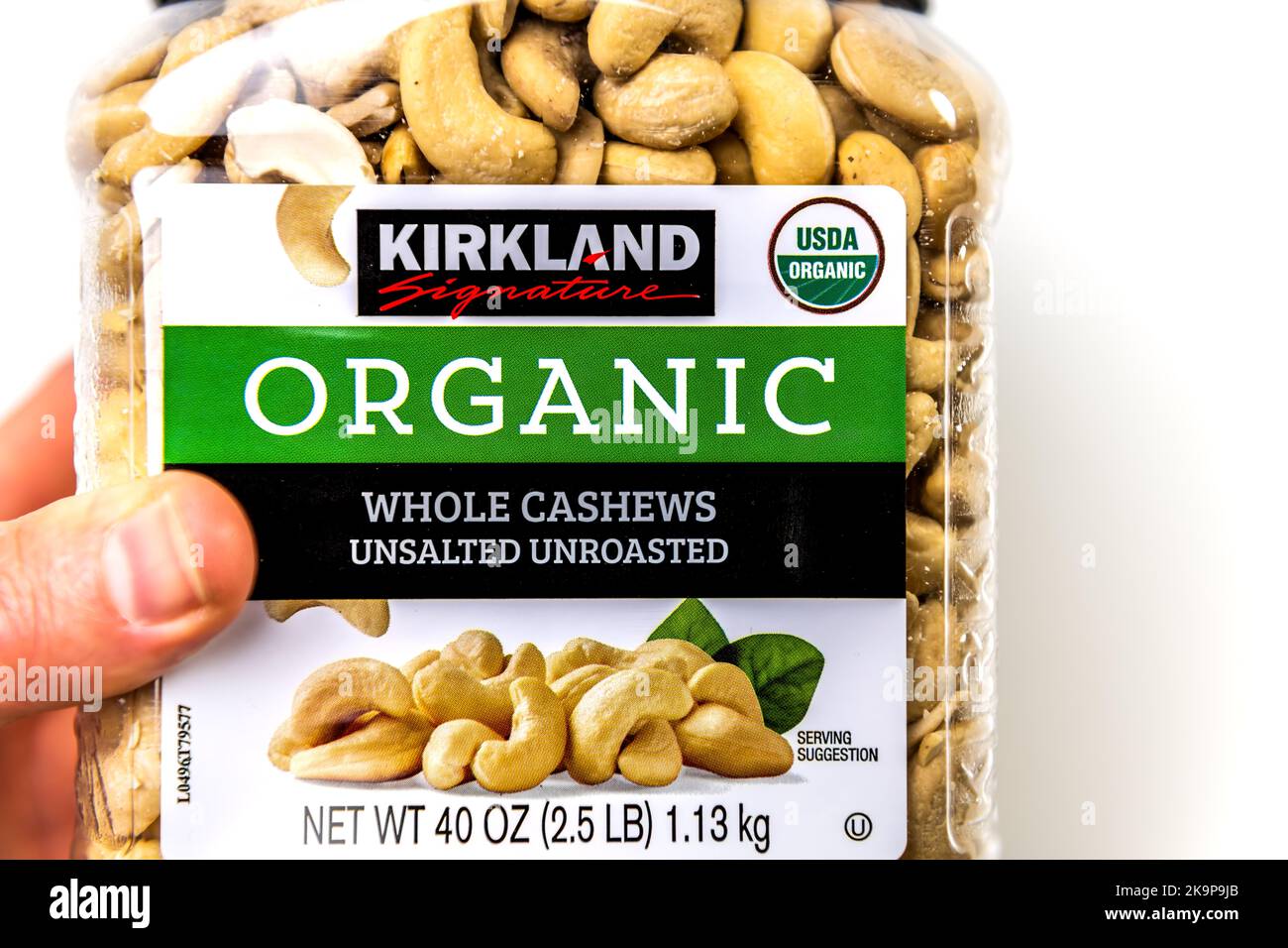 Napoli, USA - 21 ottobre 2021: Primo piano macro Hand holding Kirkland firma Costco private label di noci di acino crude non salate biologiche Foto Stock