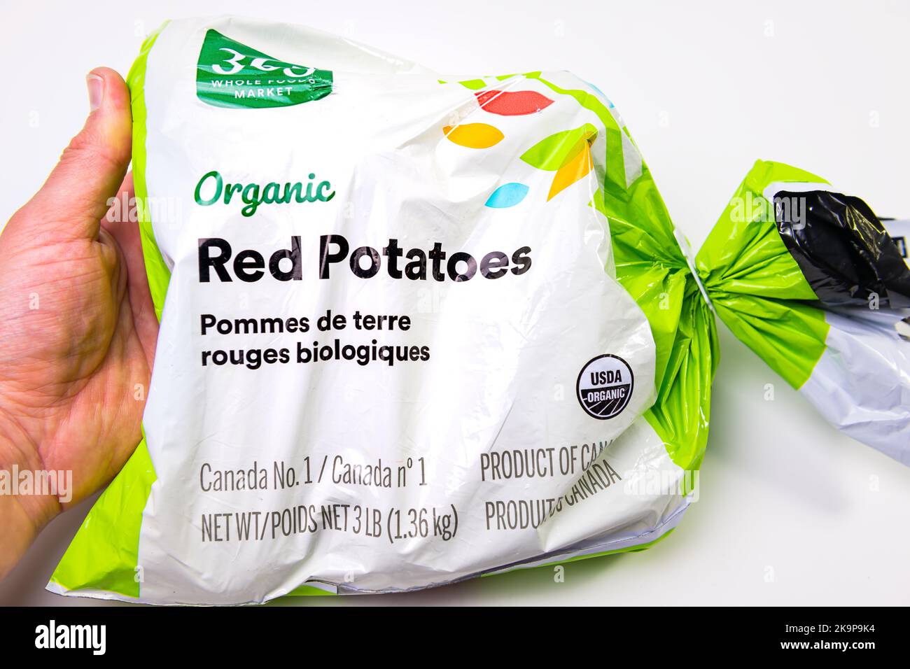 Napoli, Florida - 21 ottobre 2021: Macro closeup mano che tiene sacchetto di plastica di Whole Foods private label 365 patate rosse isolate su sfondo bianco Foto Stock