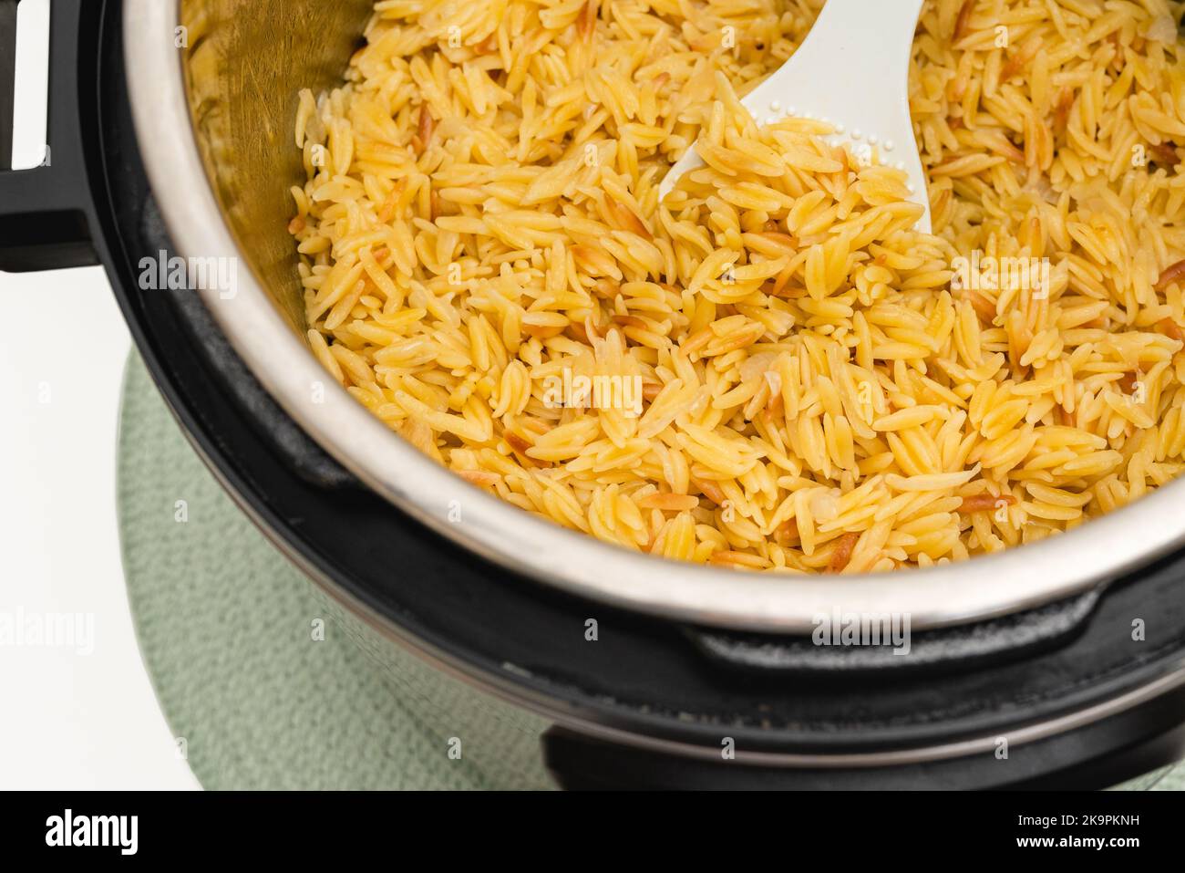 Pasta cotta in Instant Pot. Deliziosa pasta orzo primo piano in una pentola su sfondo bianco con spazio per la copia Foto Stock