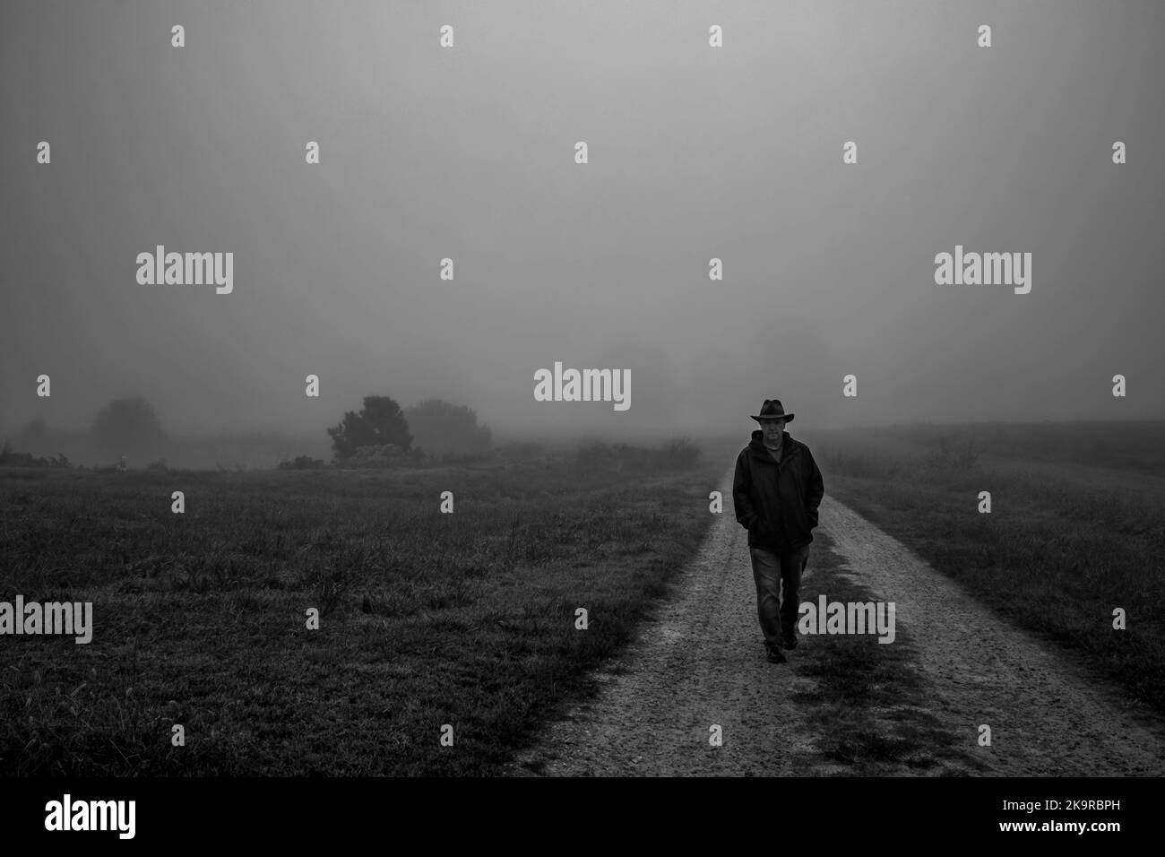 Un'atmosfera da moody come un uomo che sfreccia lungo una strada sterrata verso lo spettatore in una mattina di nebbia calma. Foto Stock