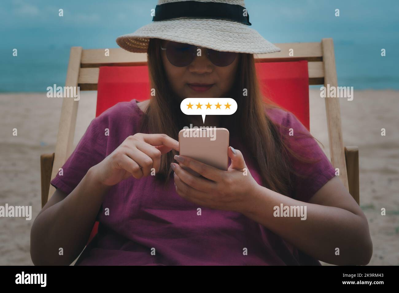 Una giovane donna usa lo smartphone con l'icona a cinque stelle a comparsa per il feedback, esamina il servizio di soddisfazione, l'esperienza di assistenza clienti e la soddisfazione aziendale Foto Stock