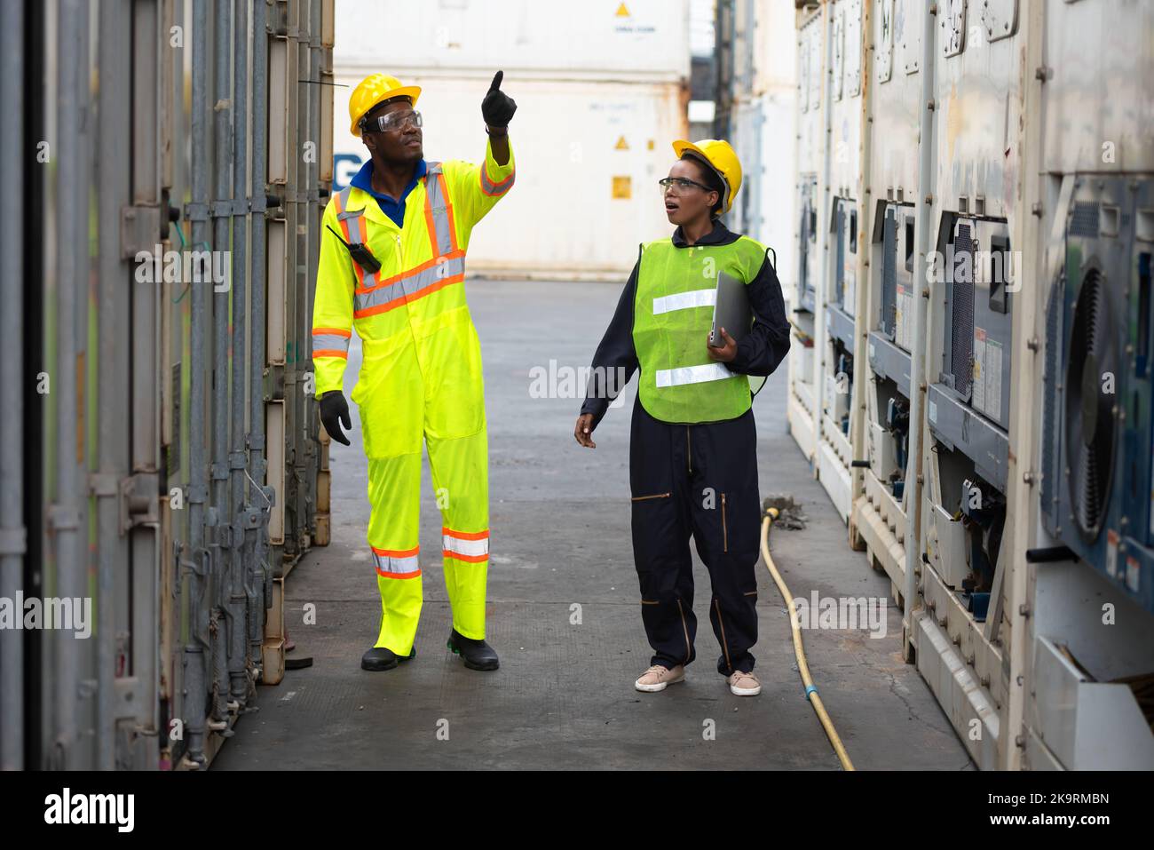 Giovani lavoratori che lavorano in magazzino, ingegneri industriali, supervisori di sicurezza e Foremen in hard Hats e giubbotti di sicurezza che camminano a Shippin Foto Stock