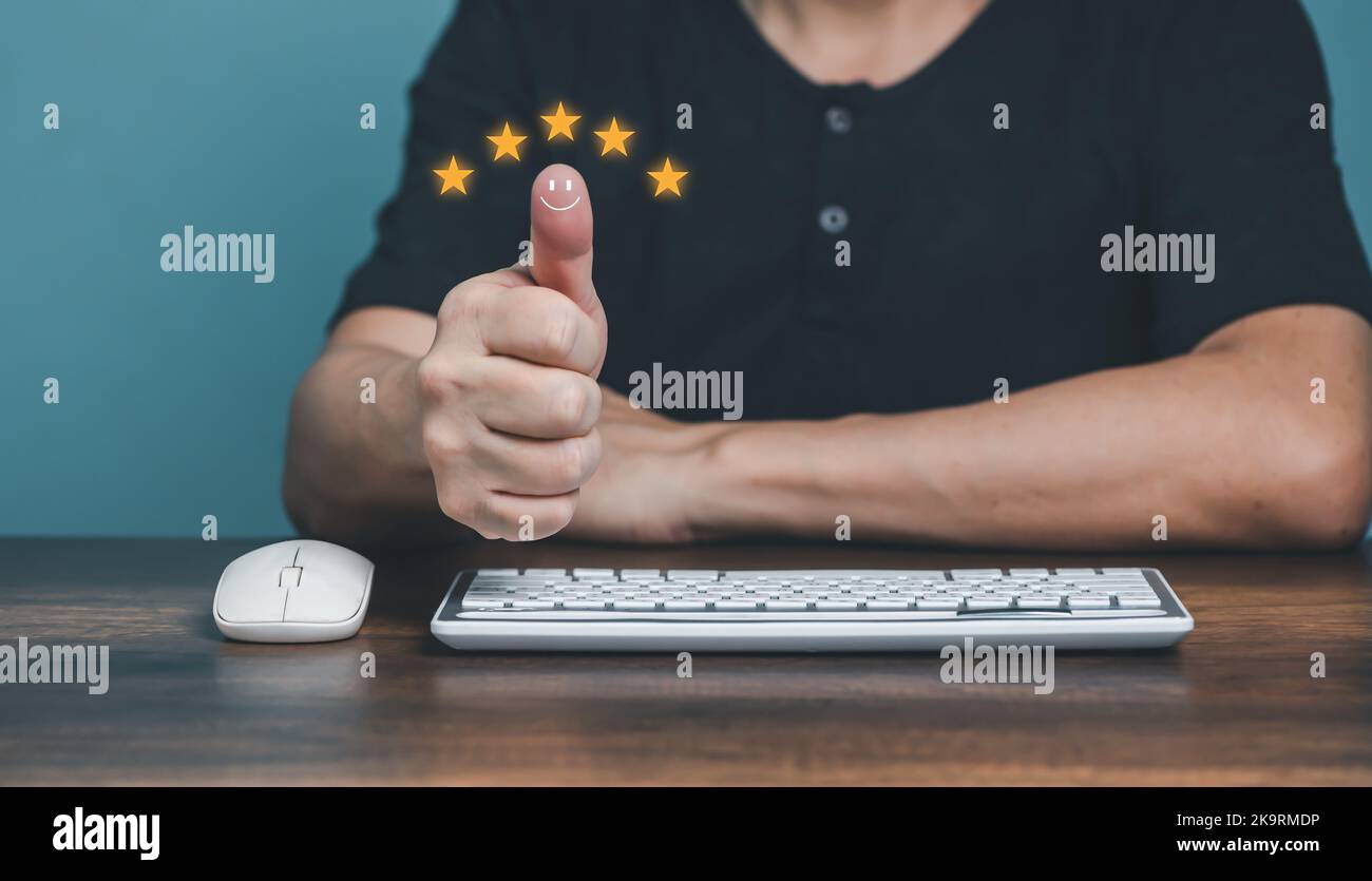 Giovane uomo che mostra i pollici in su e che dà la valutazione positiva di cinque stelle per i sondaggi di servizio di soddisfazione del cliente, cliente valutazione feedback conce Foto Stock