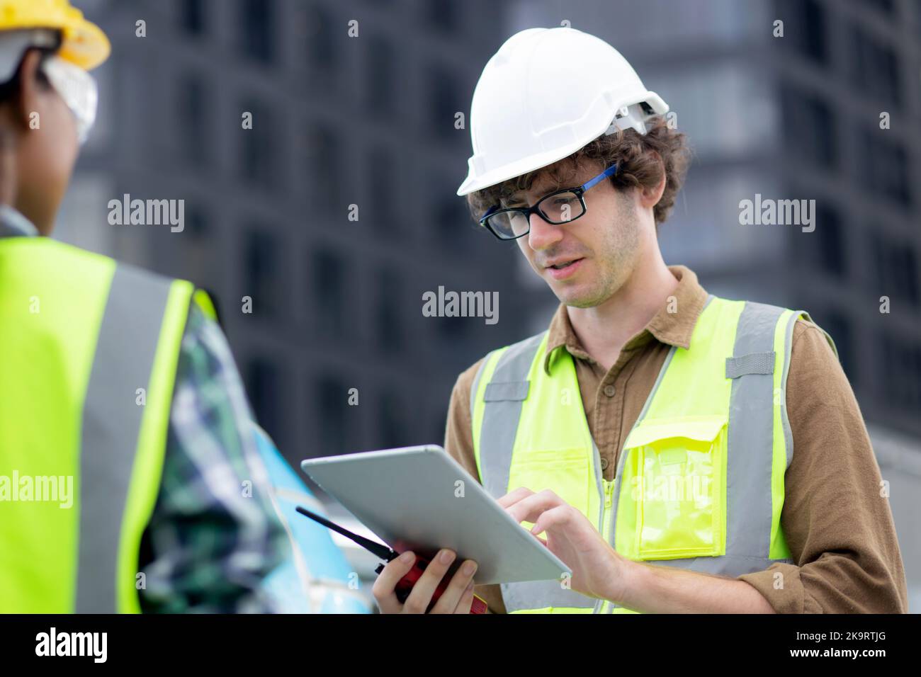 Giovane uomo e donna è architetto progettazione e ispettore progetto e guardare tablet digitale in cantiere, ingegnere di lavoro maschile e femminile e. Foto Stock