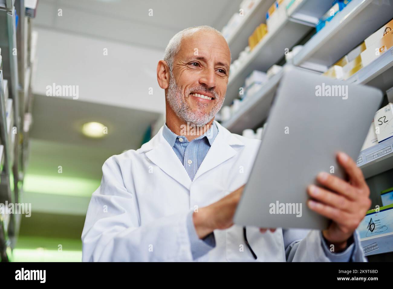Le app intelligenti rendono un servizio farmaceutico intelligente. Un farmacista maturo che utilizza un tablet digitale in farmacia. Foto Stock