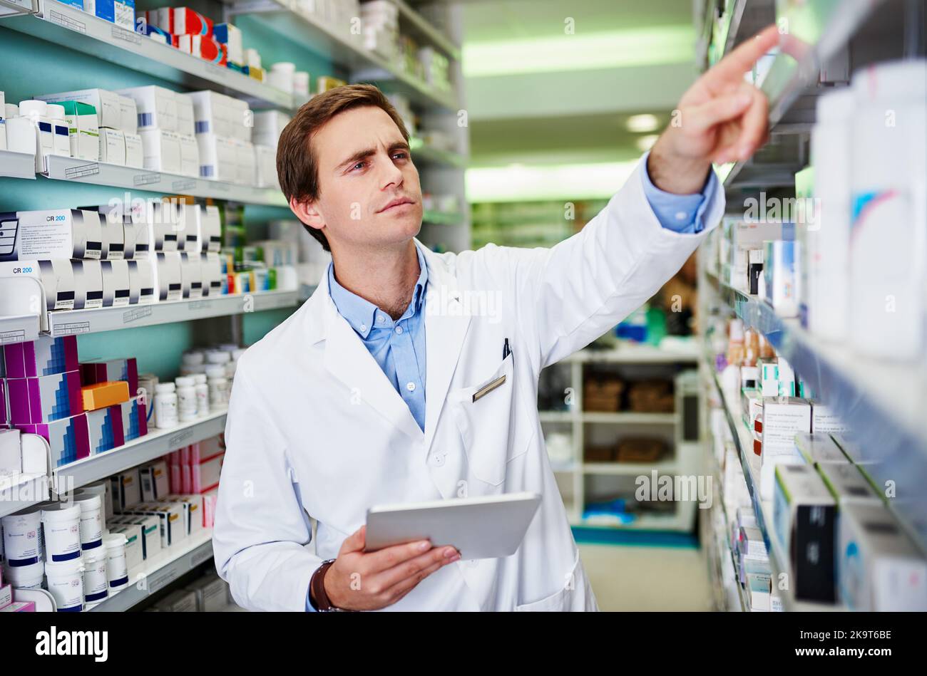 Tenere sotto controllo le ultime opzioni di trattamento disponibili. Un giovane farmacista che utilizza un tablet digitale in farmacia. Foto Stock