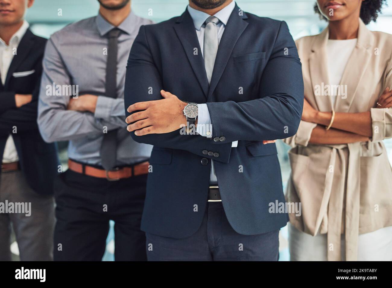 Significa affari. Un gruppo di uomini d'affari irriconoscibili in piedi con le braccia ripiegate all'interno dell'ufficio durante il giorno. Foto Stock