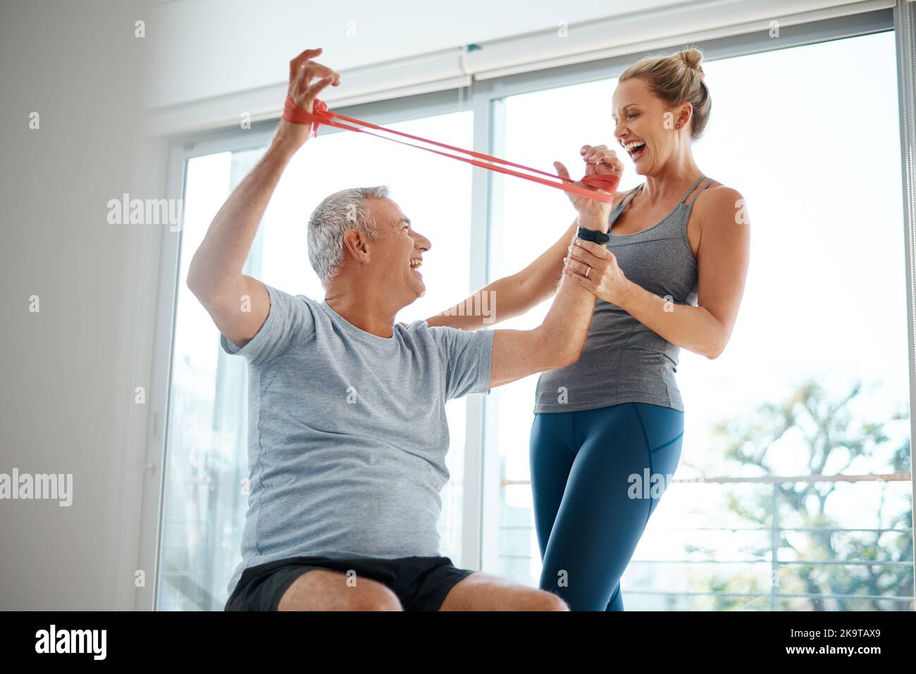 La resistenza non è assolutamente inutile. Una donna matura attraente che aiuta il marito con il suo workout nel paese. Foto Stock