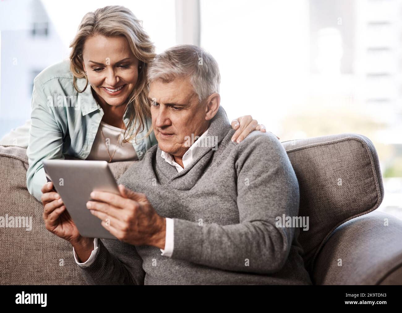Internet ha rivoluzionato il nostro modo di fare acquisti: Una coppia matura che utilizza un tablet digitale e una carta di credito per fare acquisti online a casa. Foto Stock