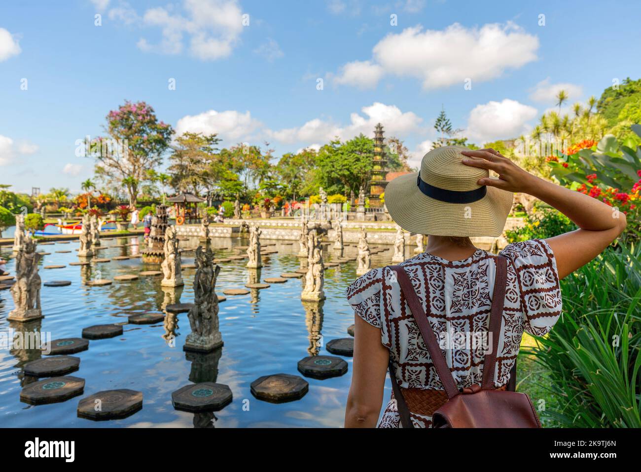 Donna che indossa abiti bianchi e cappello di paglia al tempio Taman Tirtagangga di Bali, Indonesia, in una giornata di sole Foto Stock