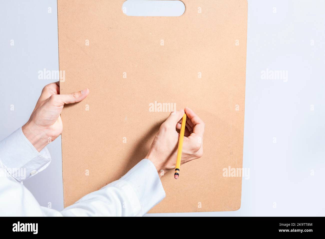 Primo piano delle mani del medico con la matita sopra gli appunti con lo spazio della copia. Il dottore scrive le mani su appunti di legno in bianco isolato. Concetto di mani Foto Stock