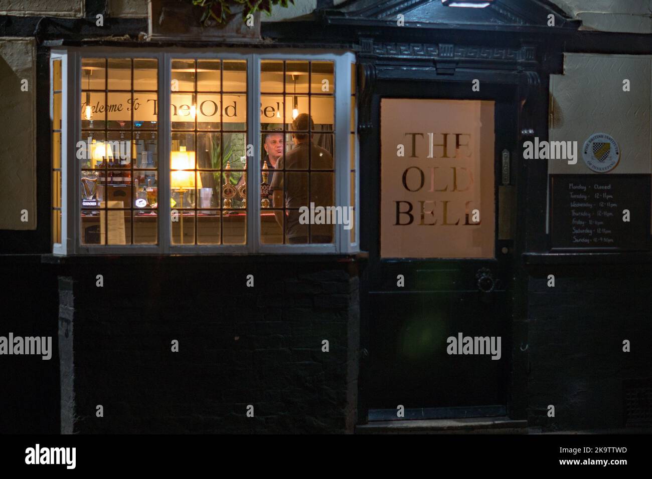 :Il pub Old Bell in via Bell a Sawbridgeworth, una vista serale attraverso la finestra frontale del padrone di casa che serve Foto Stock