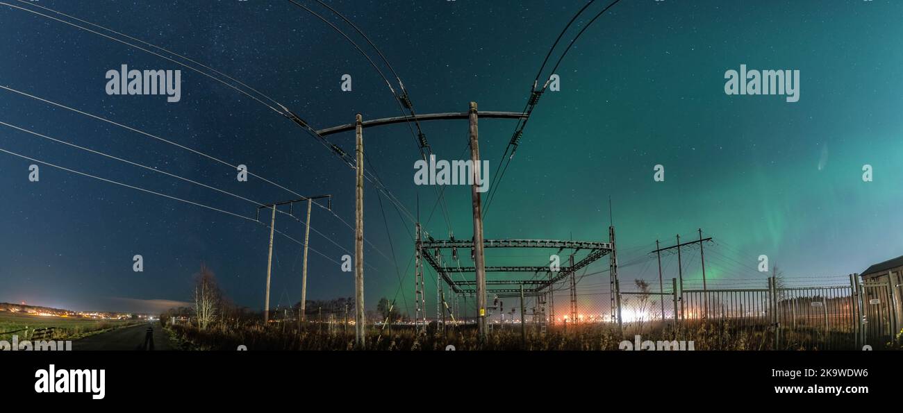 Splendido panorama notturno con Aurora sopra la sottostazione elettrica e le linee elettriche a pali in legno, cielo stellato con Aurora Borealis. Svezia, Umea Foto Stock