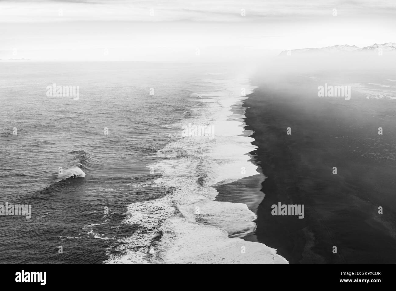 Nebbia mattutina e nuvole sopra l'infinita spiaggia di sabbia nera a Dyrholaey, Islanda Foto Stock