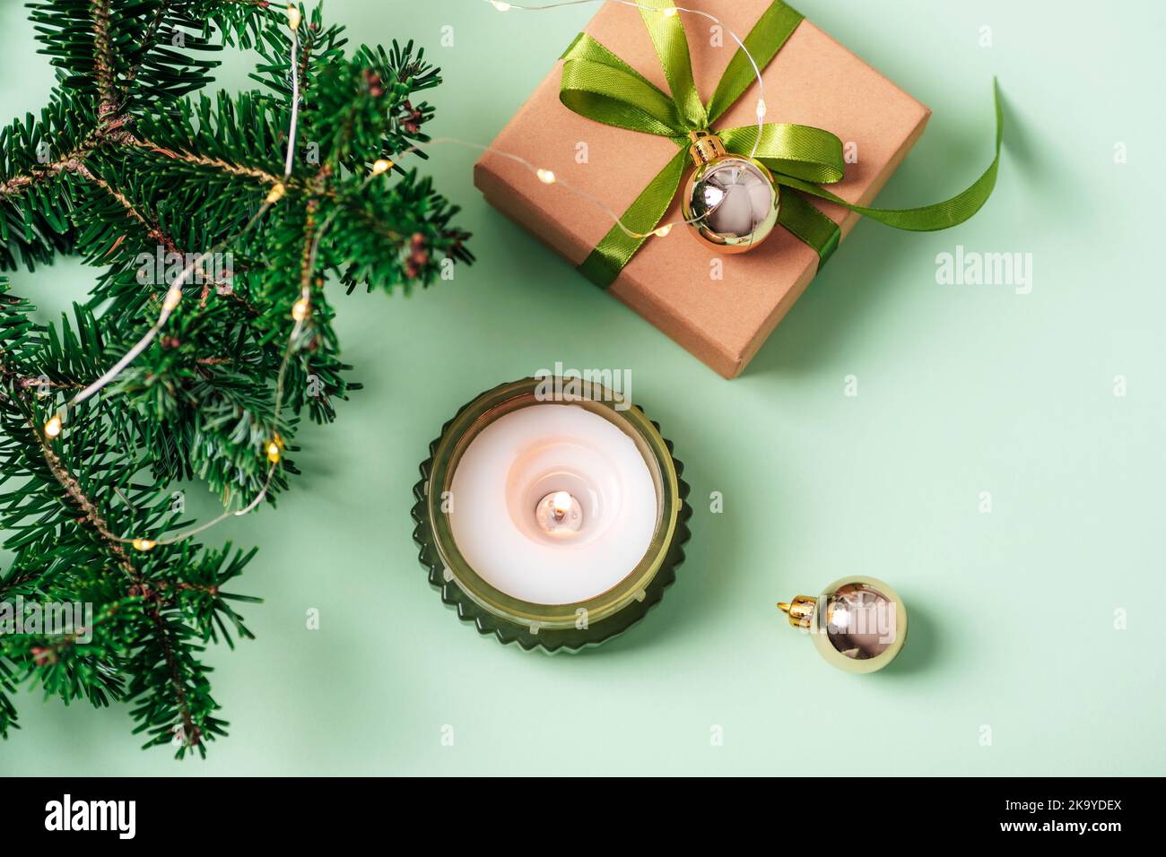 Sfondo di Natale con candela, scatola regalo, rami di abete e giocattoli di Natale su tavolo verde. Vista dall'alto, disposizione piatta. Foto Stock