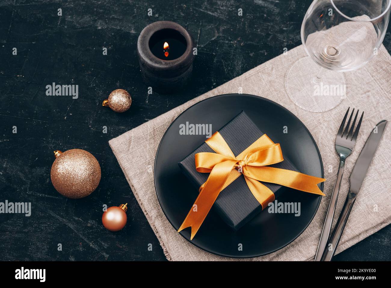 Tabella di Natale e Capodanno in nero. Piatto nero, posate, confezione regalo, candela, wineglass e giocattoli. Vista dall'alto. Foto Stock