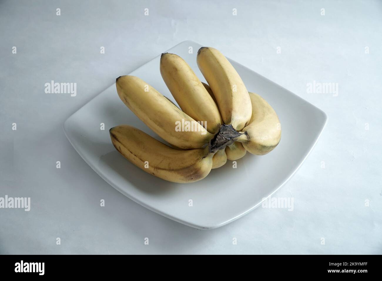 mazzo di banane su piatto bianco Foto Stock