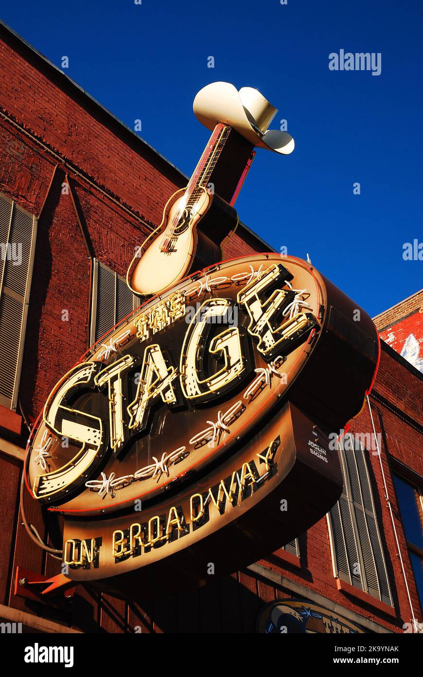 Una chitarra che indossa un cappello da cowboy si trova sul cartello per The Stage on Broadway, un leggendario locale di musica country e pop a Nashville, Tennessee Foto Stock
