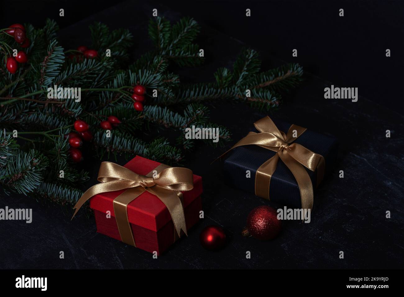 Regali di Natale, rami di abete e giocattoli di Natale su sfondo nero. Primo piano. Foto Stock