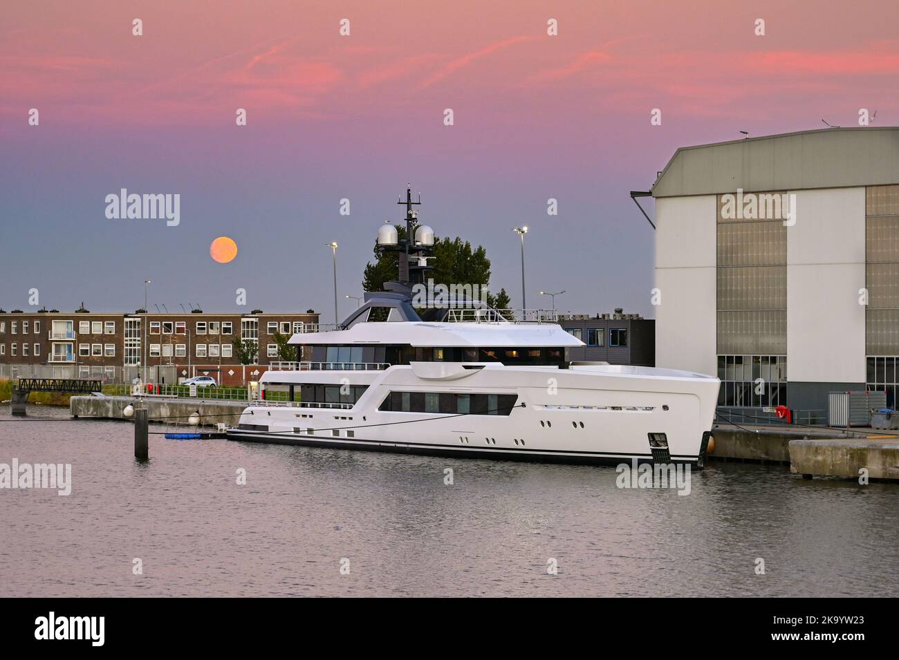 Vlissingen, Paesi Bassi - Agosto 2022: Nuovo super yacht di lusso ormeggiato fuori dalla fabbrica di yacht Damen al tramonto con la luna nel cielo Foto Stock