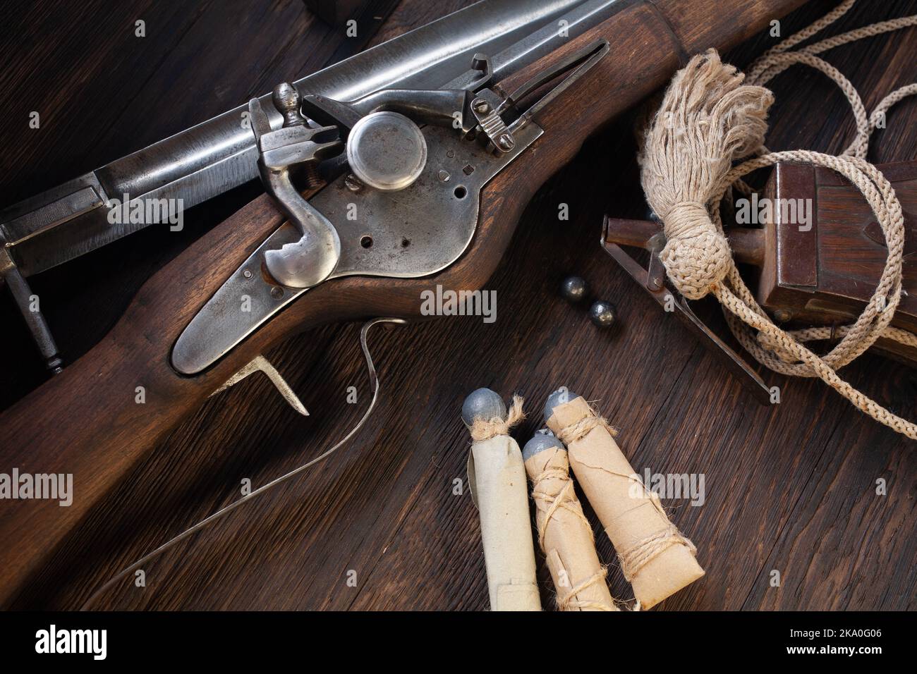 antico muschio di flintlock del xvii secolo con fiasca di polvere e pallottole a led su ponte di legno. Foto Stock