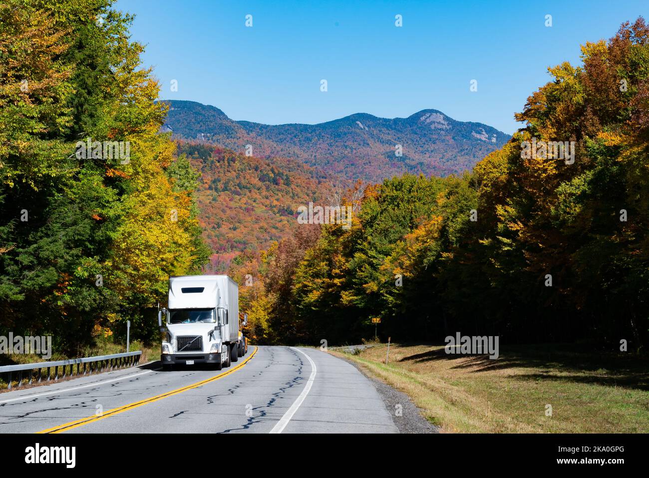 Una vista di Snowy Mountain nelle Adirondacks in autunno dall'autostrada NYS Route 30 con un camion rimorchio bianco che guida in salita. Foto Stock