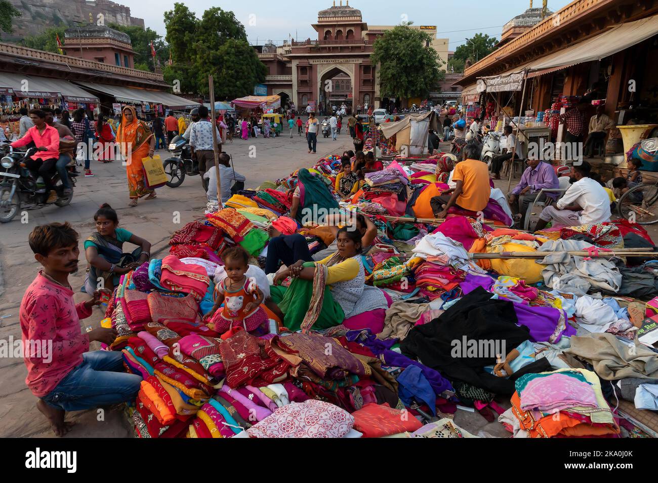 Jodhpur, Rajasthan, India - 20.10.2019 : Rajasthani Womens vestiti che sono venduti al mercato sardo famoso e Ghanta ghar Torre di orologio in serata. Foto Stock