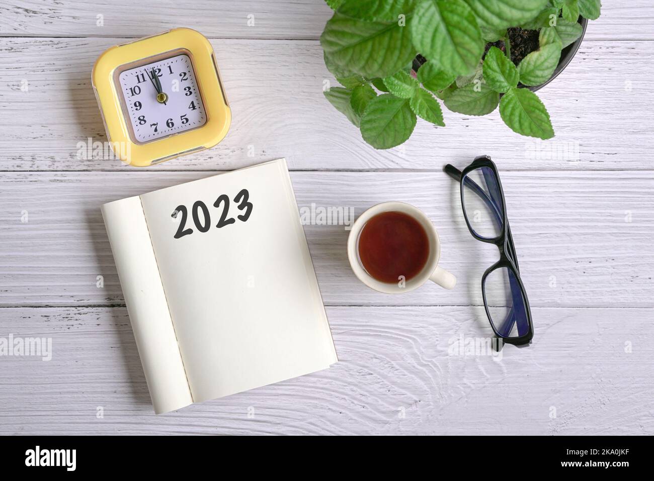 2023 sul blocco note. Vista dall'alto con caffè, orologio, occhiali e piante verdi. Foto Stock