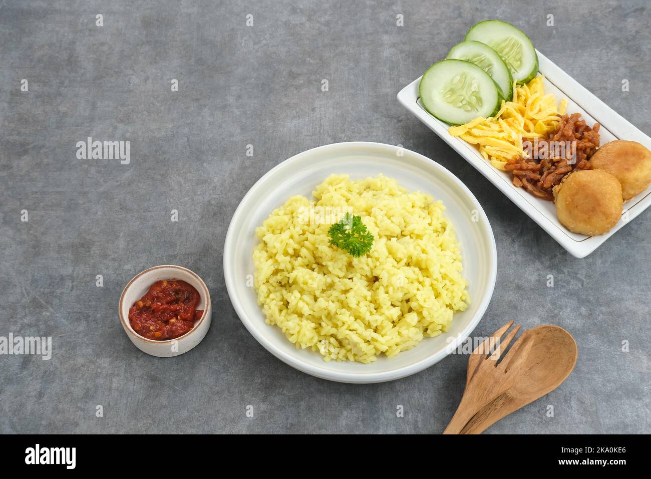 Nasi Kuning, cibo tradizionale indonesiano, a base di riso cotto con latte di curcuma e cocco e spezie, servito con vari contorni Foto Stock