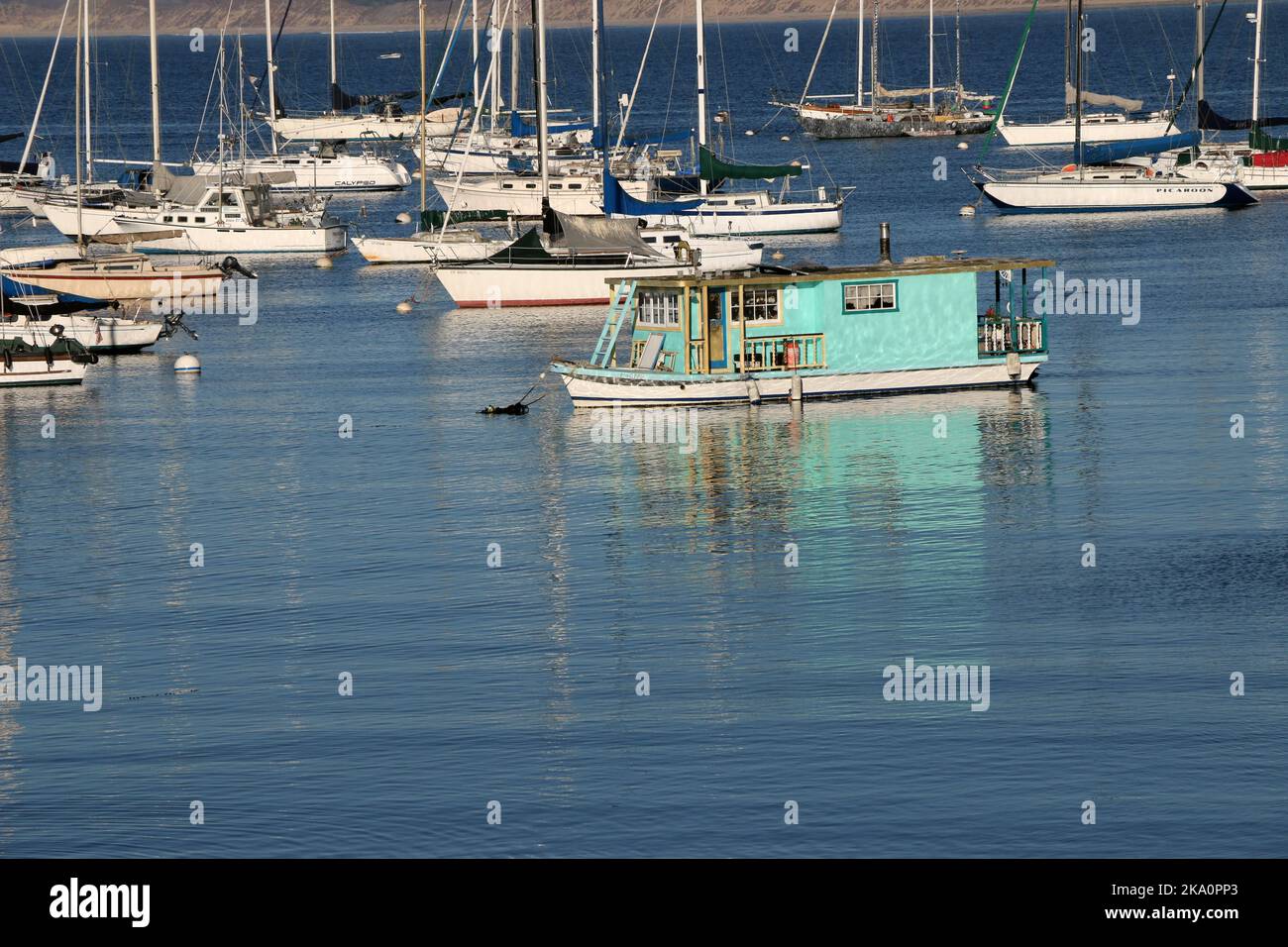 Monterey, CA, USA - 25 ottobre 2022: Una piccola houseboat blu galleggia nel porto di Monterey Bay, circondata da barche a vela e altre imbarcazioni. Foto Stock