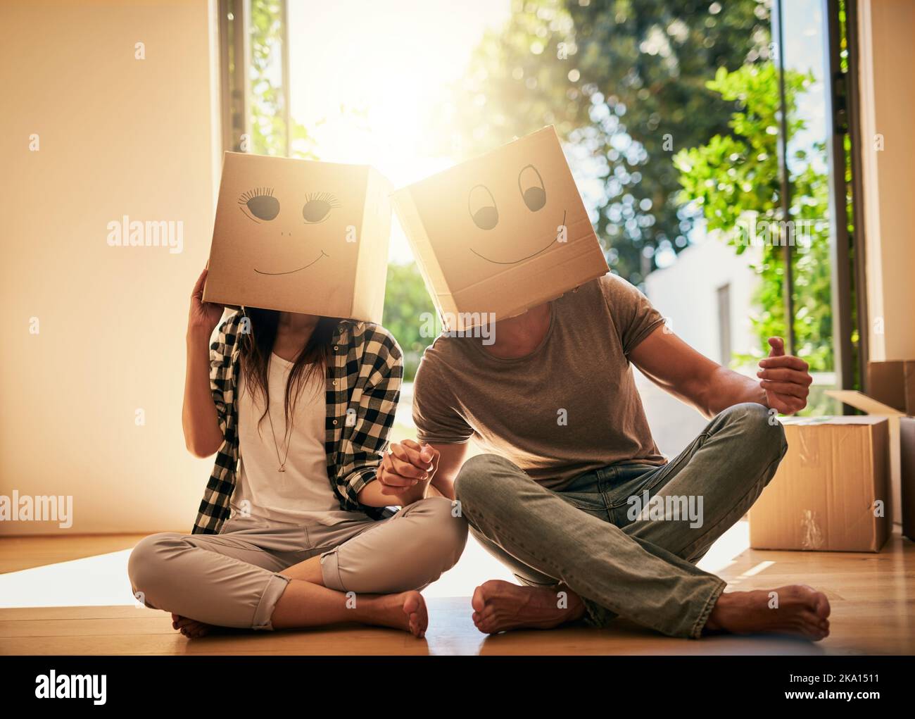 Una coppia che indossa scatole con facce sorridenti disegnate sulle loro teste. Foto Stock