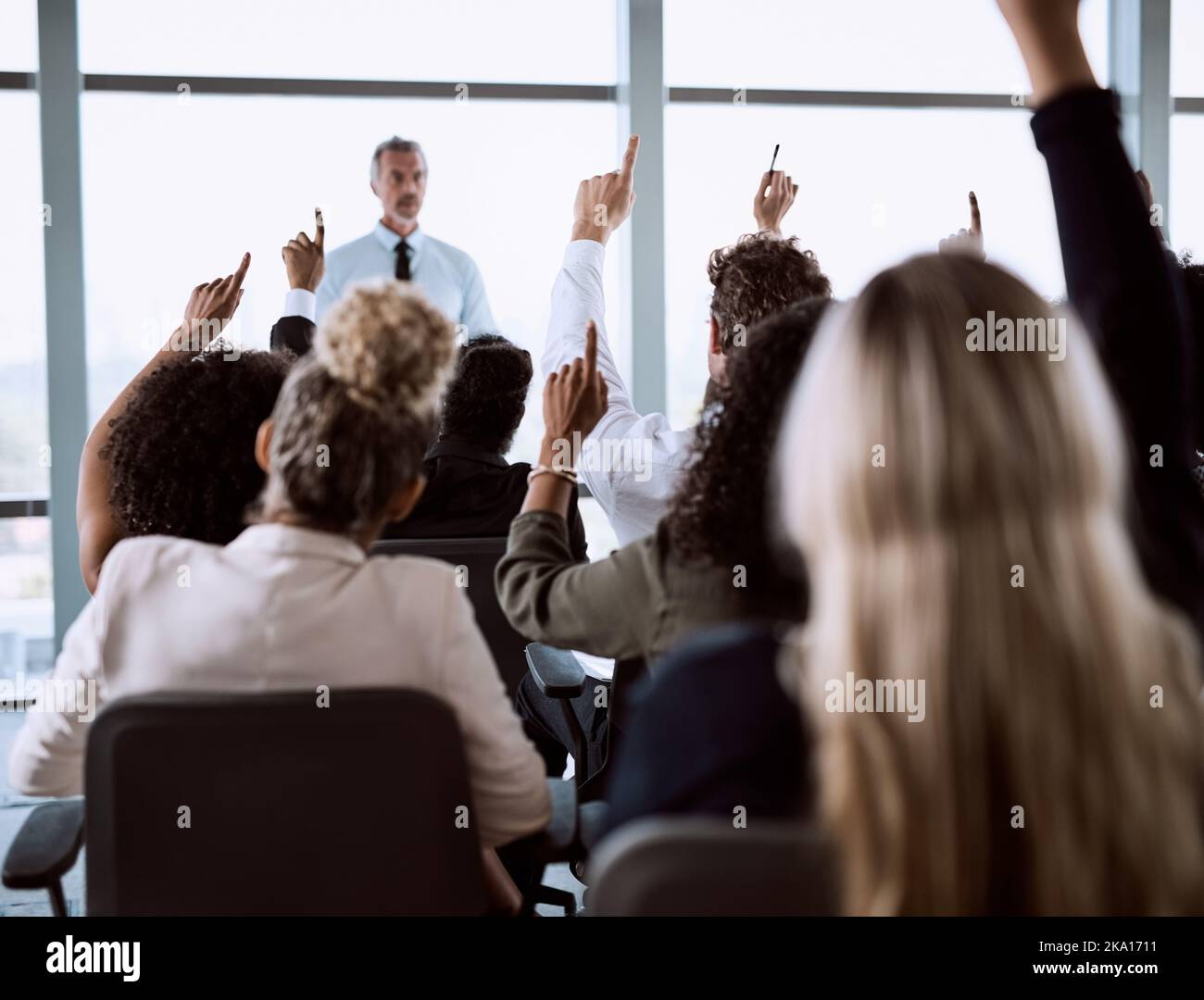 A volte è necessario un po' più di chiarimento: Un gruppo di uomini d'affari alzando le mani per porre domande durante una conferenza. Foto Stock