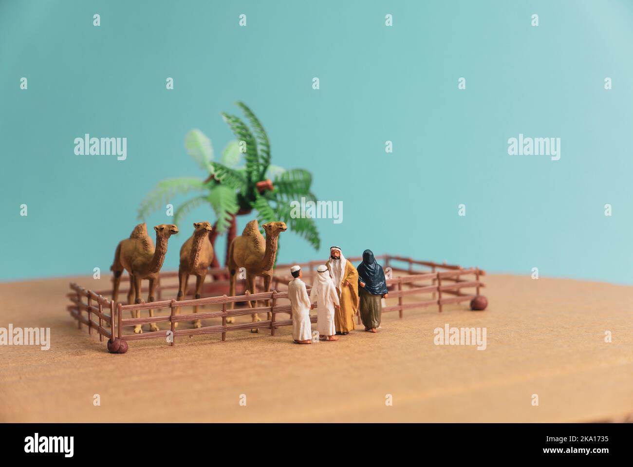 Giocattolo in miniatura l'uomo e la moglie arabi in abaya compra cammello e pecore da un bambino su un concetto di fattoria. Foto Stock