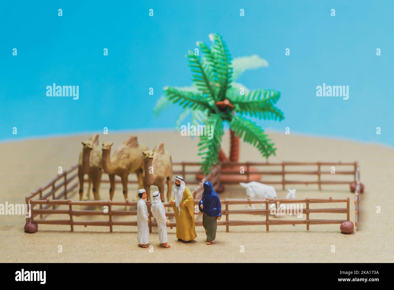 Giocattolo in miniatura l'uomo e la moglie arabi in abaya compra cammello e pecore da un bambino su un concetto di fattoria. Foto Stock