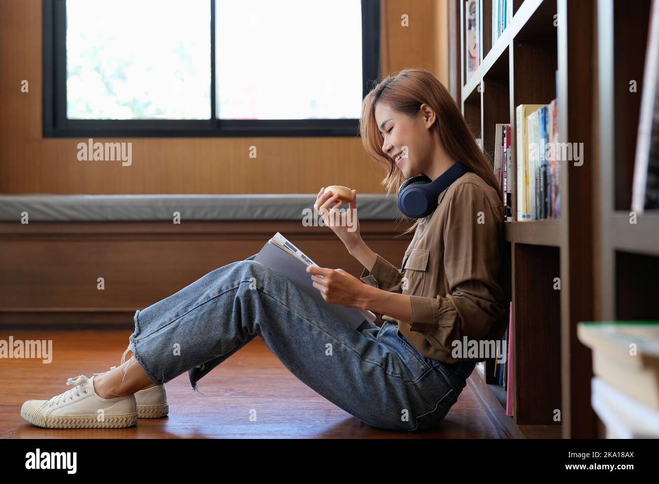 Ritratto di un giovane allievo felice che legge un libro in una biblioteca Foto Stock