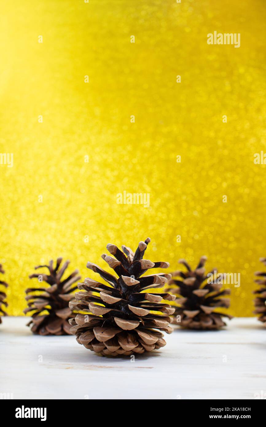 Coni di abete marrone su tavolo bianco dietro sfondo giallo sfocato. Natale, Capodanno. Spazio di copia Foto Stock