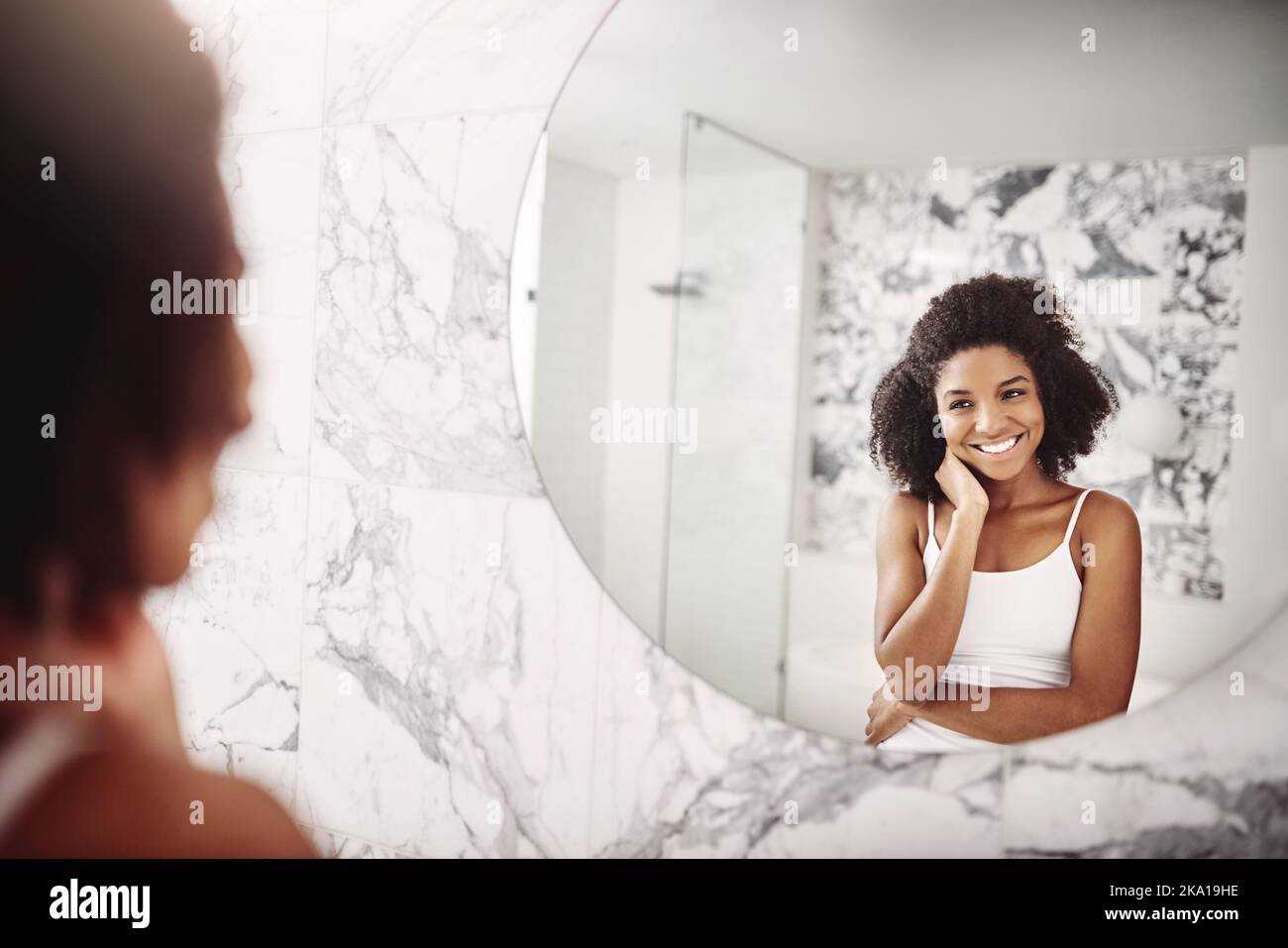 Chi non si svegliava felice con un volto come questo, una giovane donna attraente che ammirava il viso nello specchio del bagno. Foto Stock