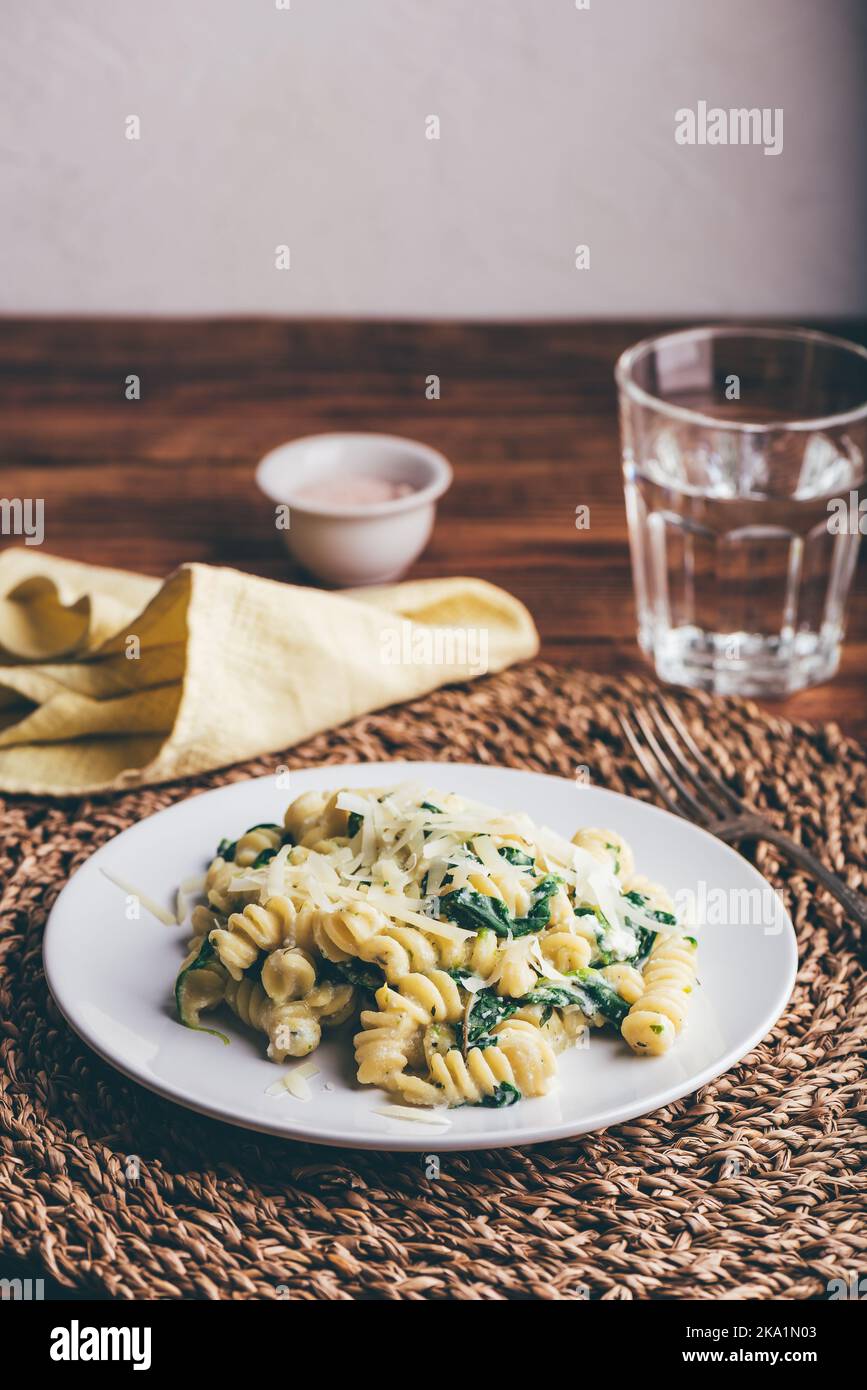Pasta di fusilli con spinaci e ricotta guarnita con parmigiano grattugiato Formaggio su piatto bianco Foto Stock
