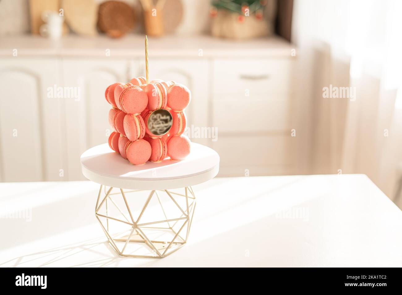 Torta con candele di macaron rosa su un supporto geometrico al sole Foto Stock