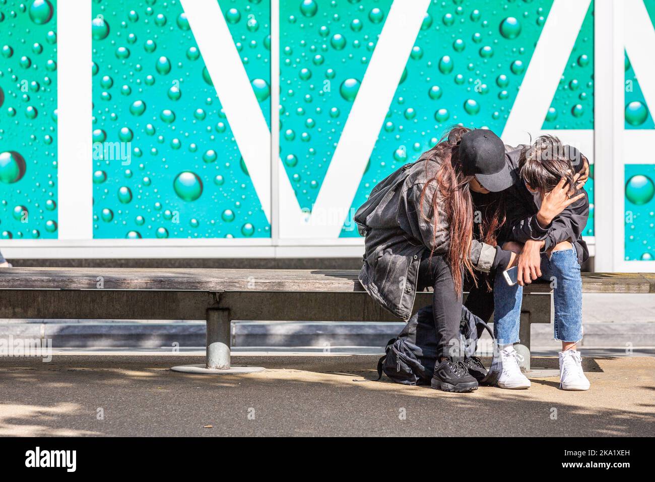 Dolore e conforto: Due figure sedute su una panchina, una afflitta, l'altra consolante la prima. Bruxelles. Foto Stock