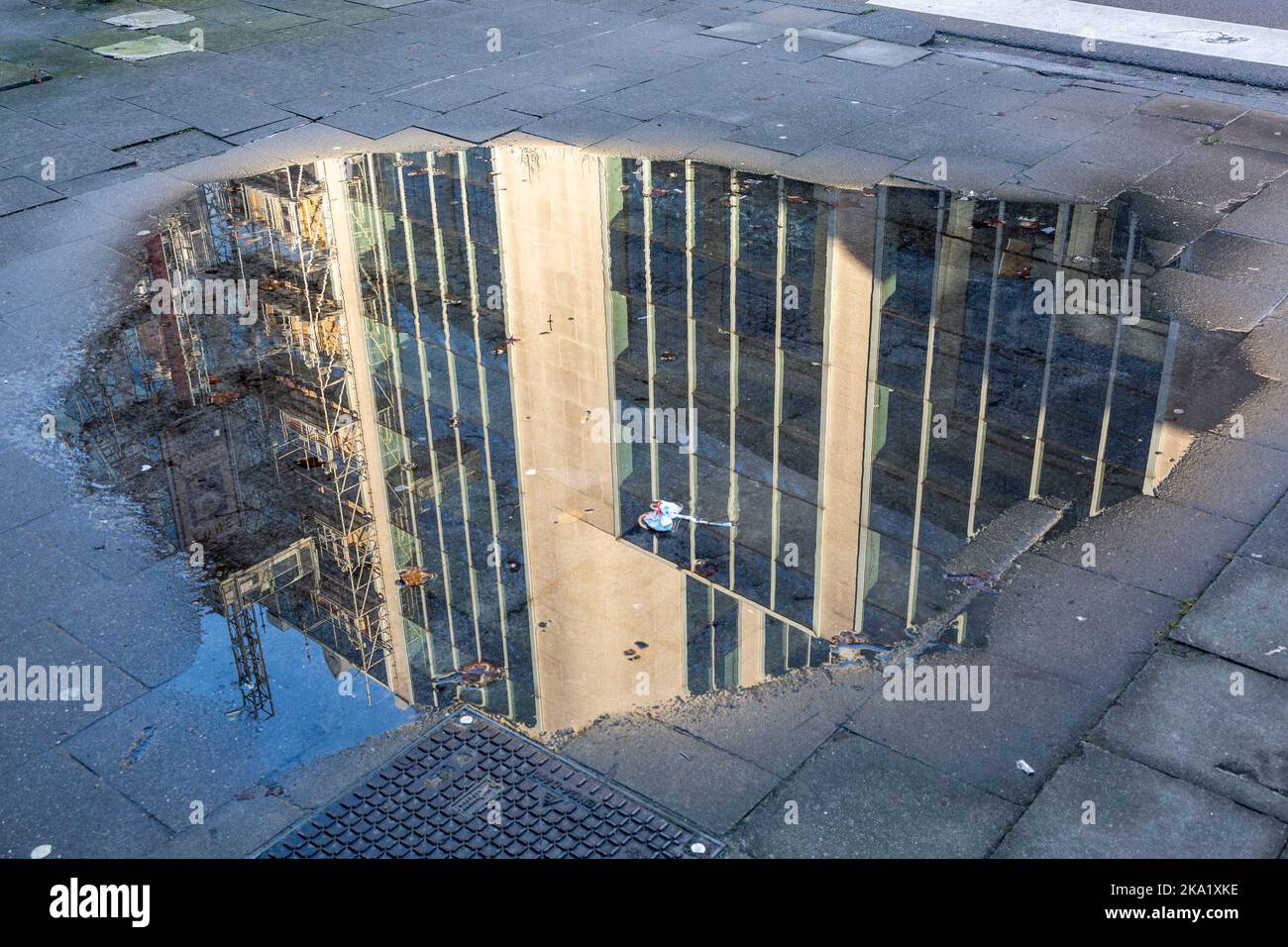 Immagine riflessa di un edificio in costruzione in una pozza su un marciapiede a Bruxelles, quartiere Gare du Nord. Foto Stock