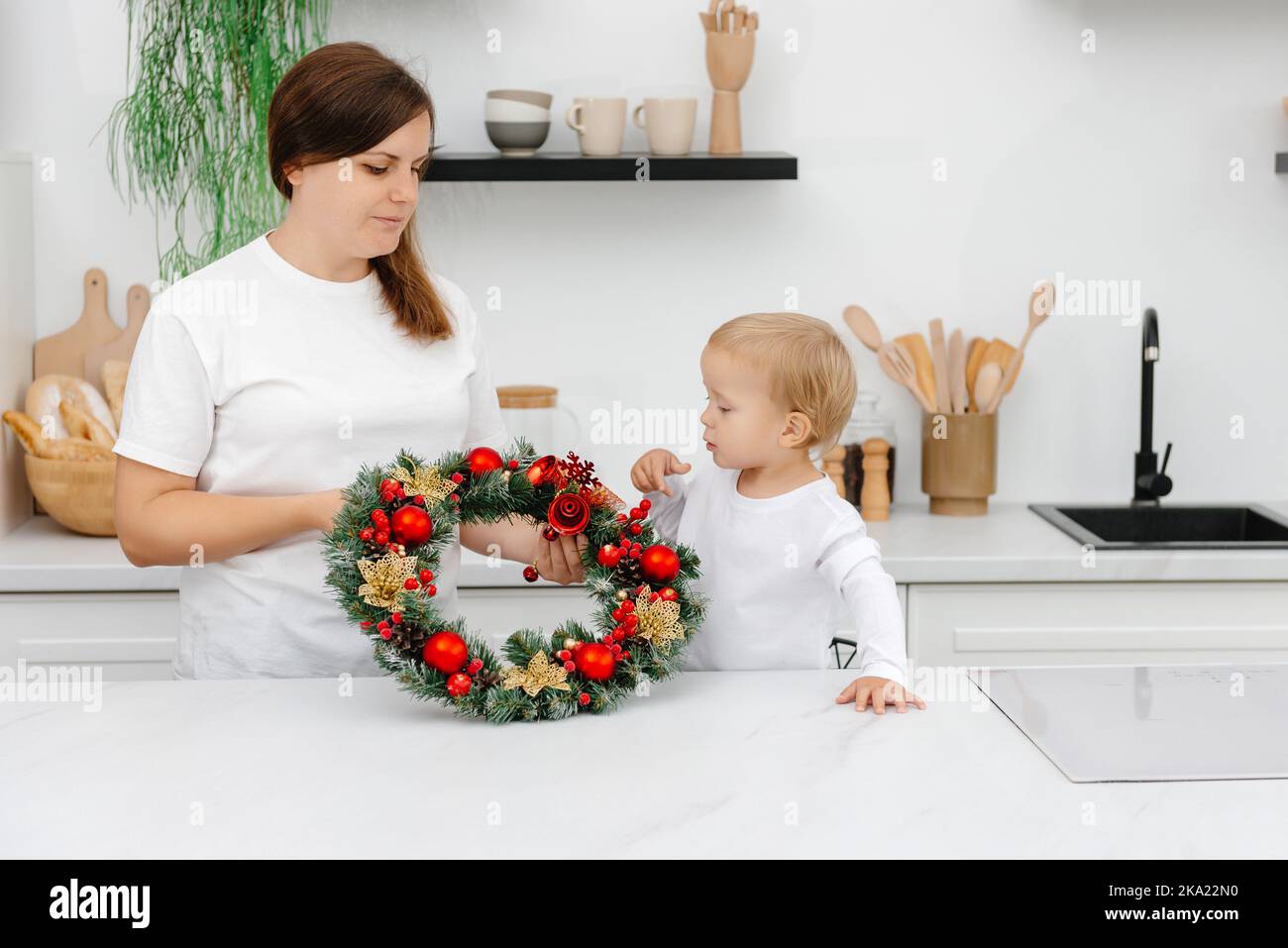 Madre e figlio in cucina con decorazioni natalizie. Preparativi per la vigilia di Capodanno Foto Stock