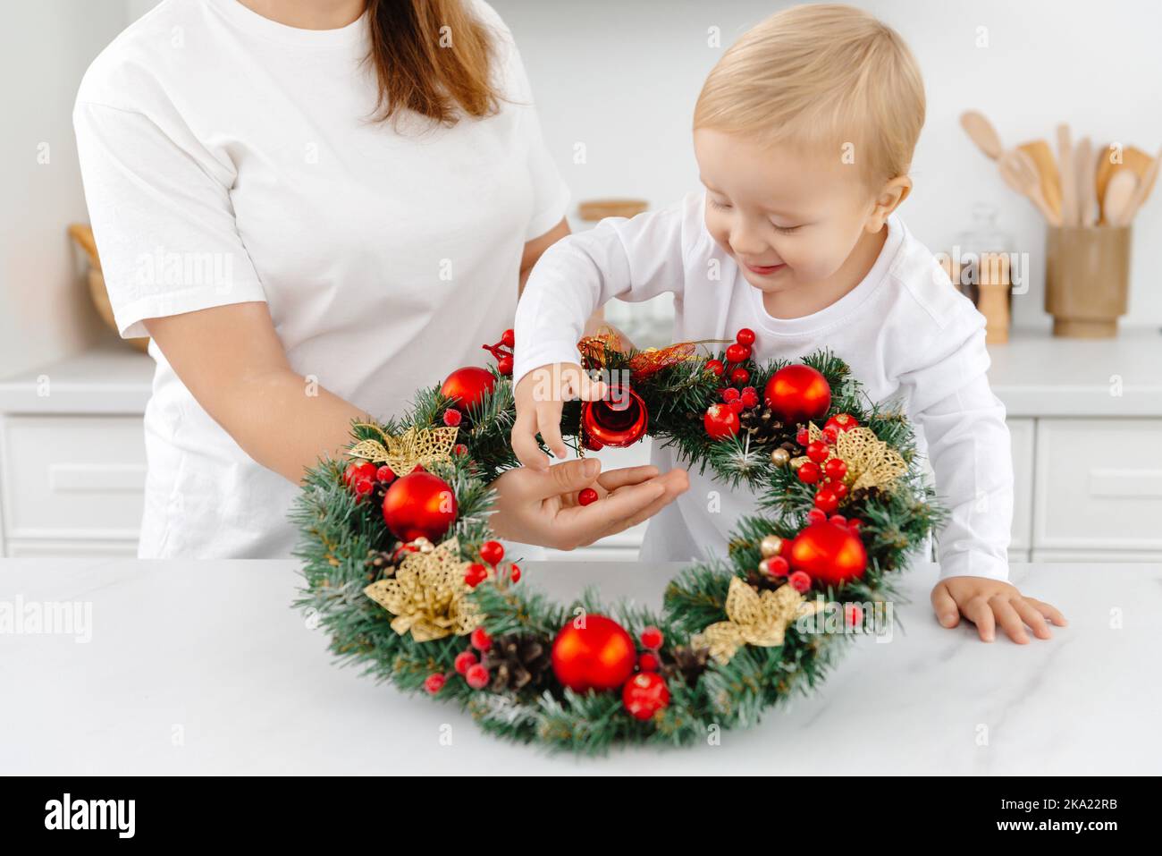 Piccolo figlio aiutante aiuta mamma con le decorazioni di Natale Foto Stock
