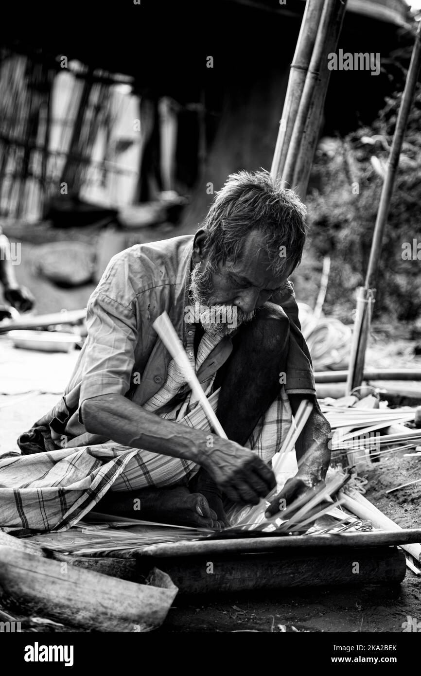 Un'immagine in scala di grigi di un vecchio che lavora in una strada Foto Stock