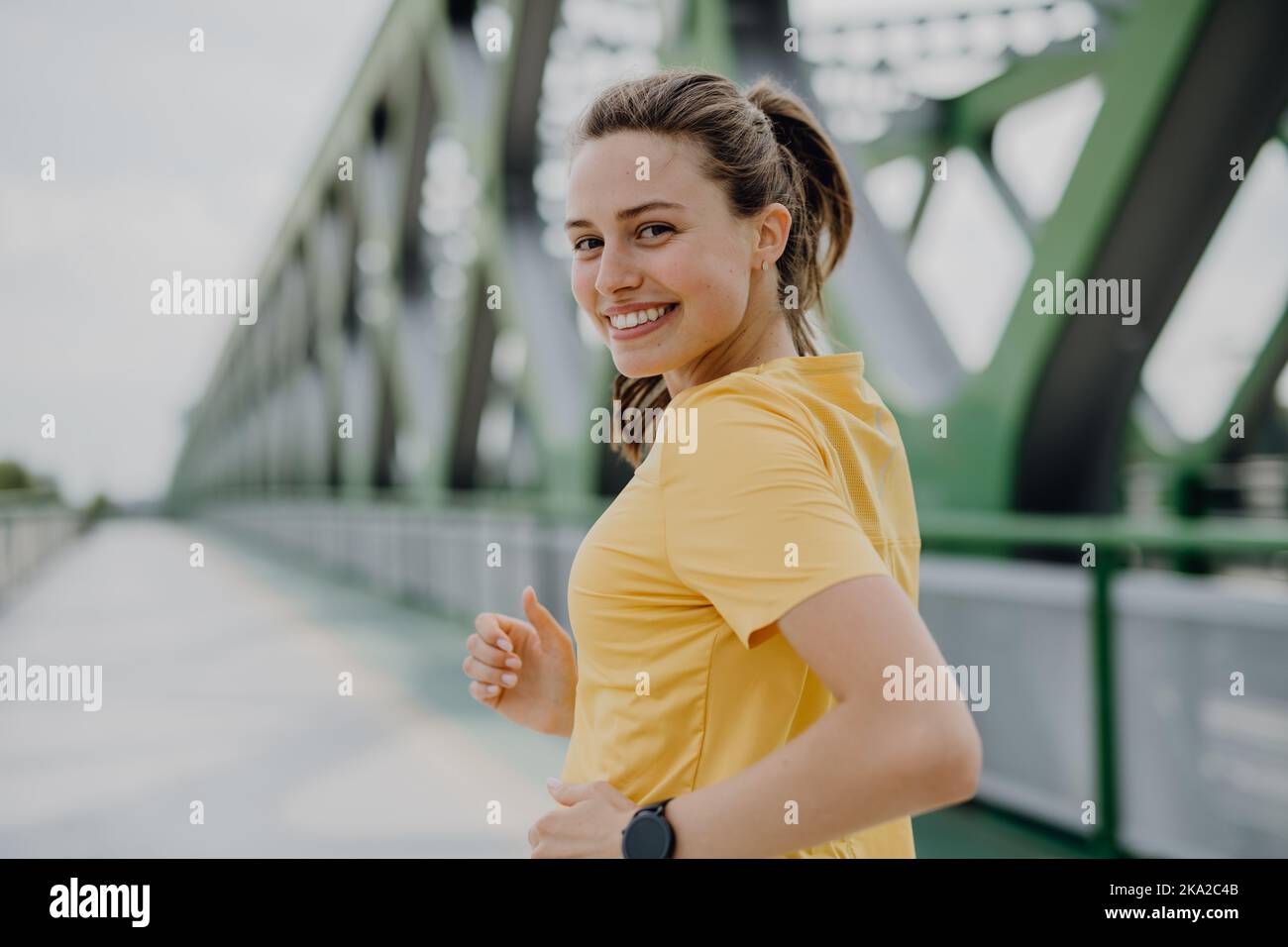 Giovane donna che fa jogging al ponte della città, stile di vita sano e concetto di sport. Foto Stock